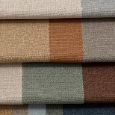 Close-up of various high-quality upholstery fabric samples in earthy tones, laid out for selection.